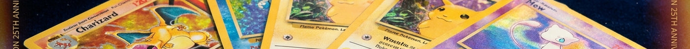 Holographic Pokémon trading cards fanned out on a dark blue surface with golden light creating rainbow reflections, with a Pokéball softly blurred in the background.